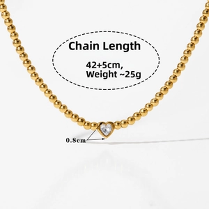 Macro d'un collier de perles dorées avec pendentif en zircon cubique serti en cœur