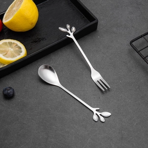 Detail of silver leaf-shaped stainless steel spoon and fork set on textured background