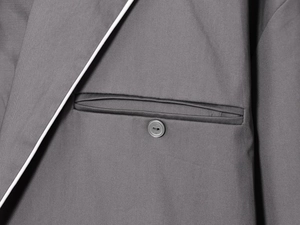 Detail of dark grey blazer featuring white contrast piping and high-quality fabric texture