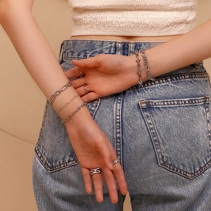 Silver stainless steel layered bracelet set and statement rings on female model