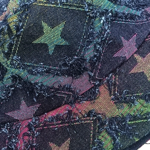 Close-up of distressed star pattern denim fabric with colorful frayed jacquard details