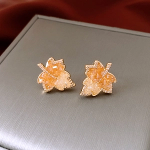 Macro shot of 14k gold plated maple leaf earrings with champagne crystals and diamonds
