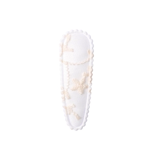 Close-up of white floral fabric hair clip with embroidered star and scalloped edges