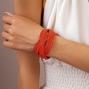 Detail of bohemian multilayer beaded bracelet with orange and gold glass beads on wrist