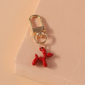Detail of red balloon dog keychain with glossy finish and gold-tone metal clasp