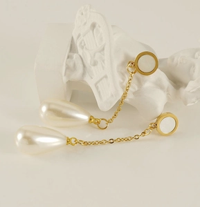 Detailed macro view of 18K gold-plated steel chain earrings with large drop pearls