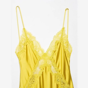 Lace-trimmed yellow satin midi dress with spaghetti straps in a minimalist flat lay view