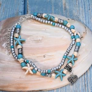 Detail of layered beach anklet with turquoise beads and starfish charms on a seashell