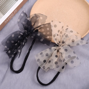 Detail of two polka dot mesh bow hair bun makers in black and beige finishes.