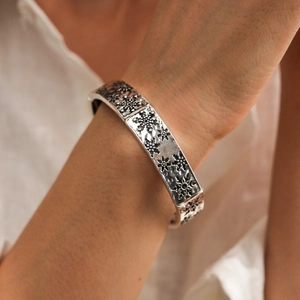 Gros plan d'un bracelet élastique argenté avec flocon de neige gravé sur le poignet