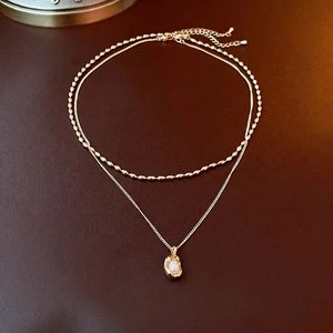 French style double-layer gold necklace with irregular pearl pendant on leather background