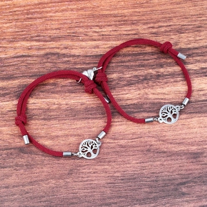 Detail of red braided couple bracelets with magnetic heart and tree of life charms