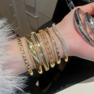 Close-up of stacked 18k gold plated bracelets featuring heart charms and zircon stones