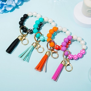 Detailed view of colorful silicone bead wristlet keychains with tassels on a blue background