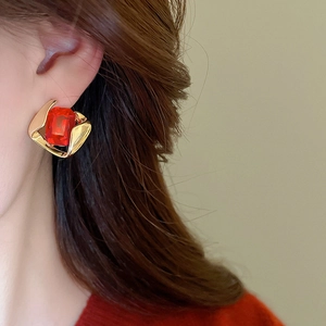 Close-up of model wearing vintage golden geometric earrings with red square crystal