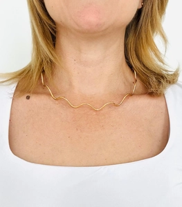 Close-up of golden wavy choker necklace on model showing minimalist style and high polish