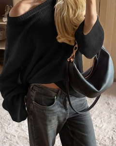 Detailed view of women black off-shoulder knitted sweater with chic leather crescent handbag