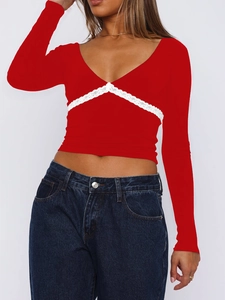 Détail d'un crop top rouge à col en V avec dentelle blanche délicate et manches longues