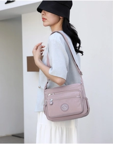 Pink nylon crossbody bag with multiple zippers shown on model for daily casual style