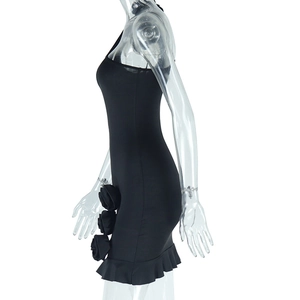 Detail of black mini dress featuring 3D rose embellishments and a ruffled hemline