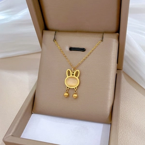 Close-up of gold rabbit pendant with cat eye stone in a beige jewelry box