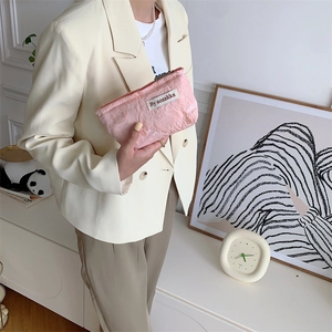 Detail of pink quilted jacquard cosmetic bag held by a model in a minimalist home setting