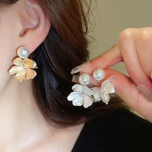 Detail of floral earring with faux pearl and white petals shown on model and hand