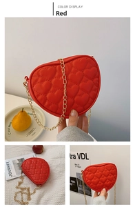 Detail of red heart-quilted PU leather kids crossbody bag with golden chain strap