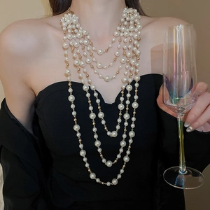 Elegant multi-layer pearl necklace with gold accents worn by a model in black attire