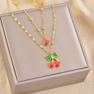 Elegant gold double-layer necklace with red cherry pendant and bead on jewelry box