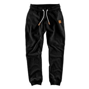 Detail of black jogger pants with white drawstring and brown square patch on pocket