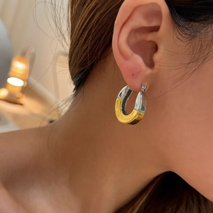 Detail showing two-tone gold and silver C hoop earrings on model with polished finish