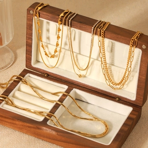 Detail of diverse 18K gold plated layered necklaces in a premium walnut wood jewelry box