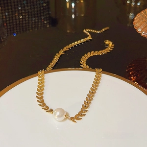 Baroque pearl necklace with gold wheat leaf chain elegantly displayed on white plate