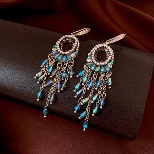 Detail of ethnic gold earrings with zircon cut beads and hanging metal chain tassels