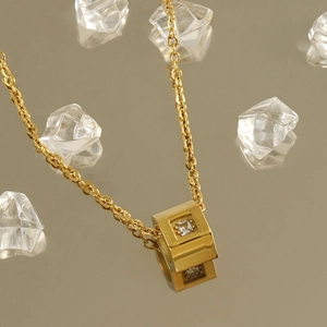 Minimalist gold stainless steel necklace featuring a geometric cubic pendant with zircon