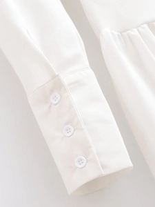 Detailed macro view of white batwing sleeve cuff featuring three buttons and pleated fabric