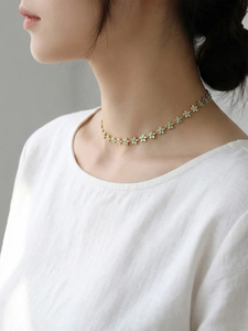 Vue détaillée du collier plaqué or 18k avec pendentifs marguerites bleues porté par modèle