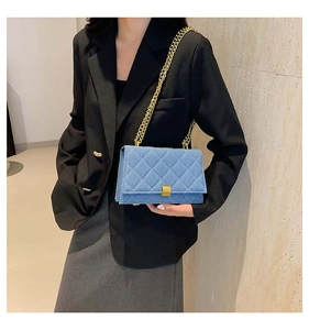 Blue denim quilted square bag with gold chain strap shown on black suit blazer