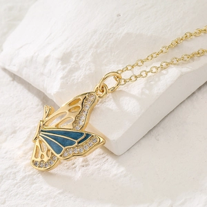 18K gold-plated butterfly necklace with blue enamel and zircon stones on stone background