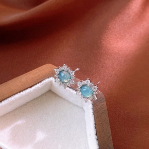 Gros plan de boucles d'oreilles fleur avec pierre sarcelle et halo de cristaux brillants