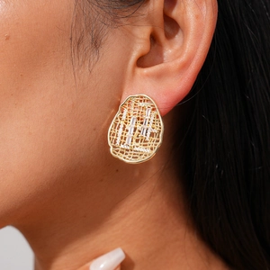 Detail of 18k gold plated hollow oval earring with zircon stones worn by a model