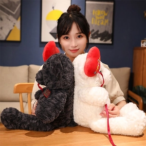 Detail of plush teddy bears in black and white with red heart embroidery held by a model