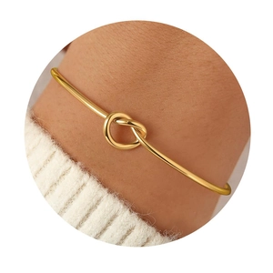 Minimalist gold knot cuff bangle bracelet with polished finish on a model's wrist