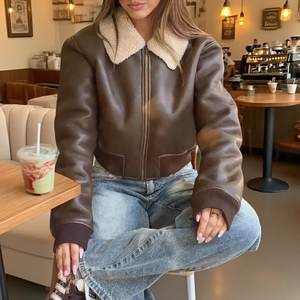 Women's dark brown faux leather jacket with cream fleece collar in a cafe setting