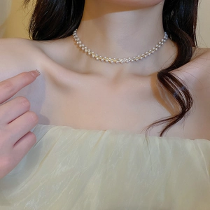 Detail einer vergoldeten Halskette mit weißen Perlen am Hals für einen eleganten Look