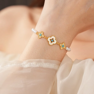 Dettaglio di un bracciale a quadrifoglio placcato oro 18k con perle e pietre turchesi