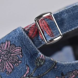 Macro detail of denim baseball cap with floral print and silver adjustable metal buckle
