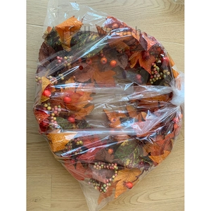 Close-up of autumn wreath with maple leaves and berries inside protective packaging