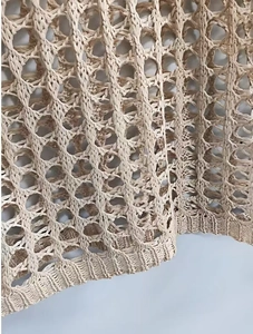 Gros plan sur la maille crochetée beige avec motifs ajourés et détails de bord-côte fin